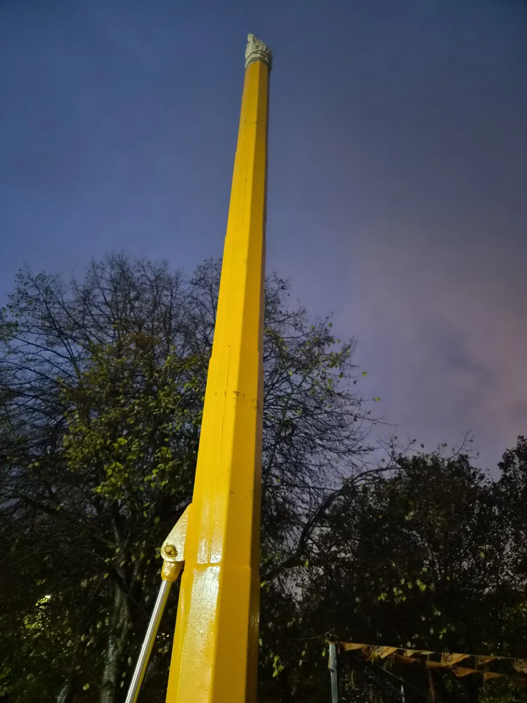 The tall yellow Nishan Sahib pole rising against the evening sky