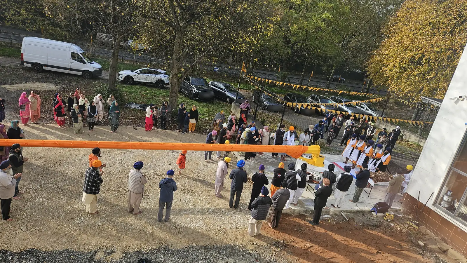 View from above of the Nishan Sahib in its orange Chola Sahib laid out across the grounds, with the sangat around it