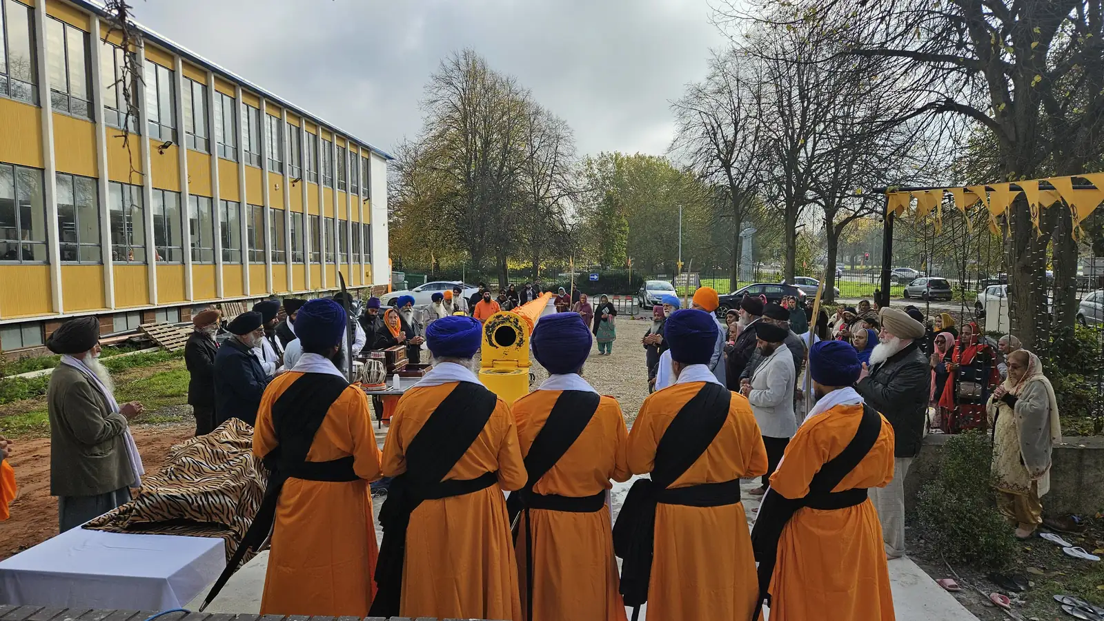 The Panj Pyare and the sangat standing with joined hands around the yellow base for Ardas