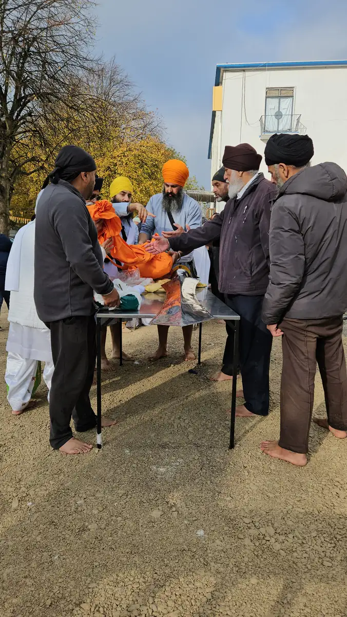 Sevadars preparing the new orange Chola Sahib at a table