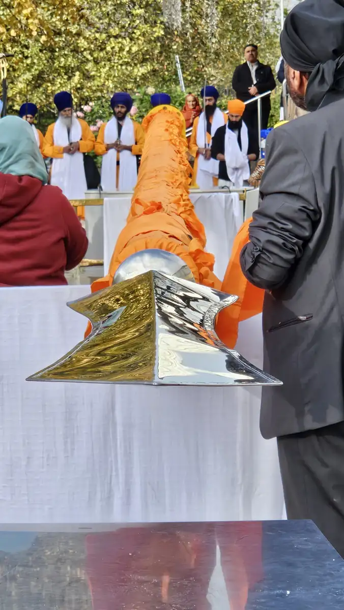 Close view of the mirror-polished Khanda at the tip of the Nishan Sahib