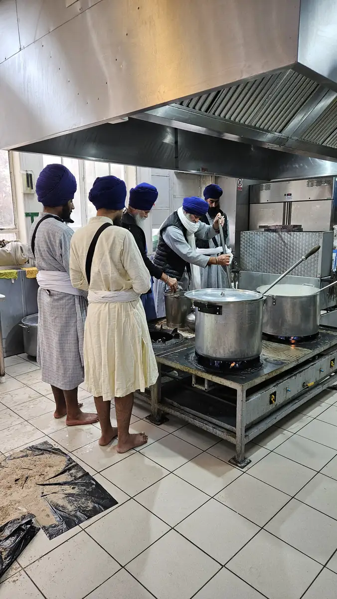 Sevadars in the langar kitchen cooking in large steel pots