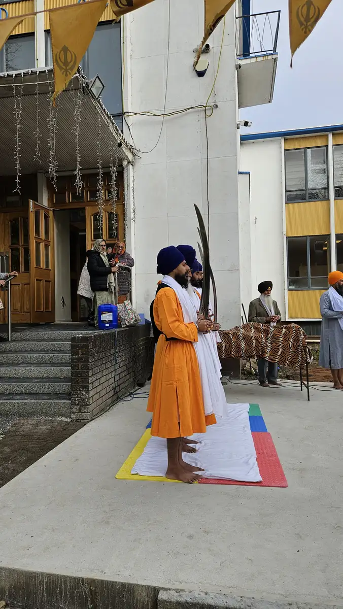 The Panj Pyare in orange bana standing at the Gurdwara entrance